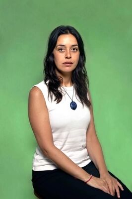 Portretfoto maker Ada Ozdogan van Het Zuidelijk Toneel, poserend tegen een groene achtergrond.