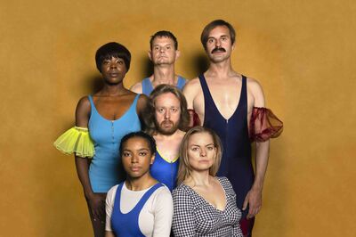 Campagnebeeld voor We Are The World, We Are The Brabant, met zes performers in kleurrijke turn- en danstenues die in twee rijen voor een okergele achtergrond poseren.