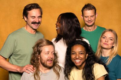 Groepsfoto ensembleleden Het Zuidelijk Toneel, , die poseren tegen een okergele achtergrond.