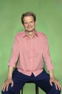 Portretfoto ensemblelid Gillis Biesheuvel van Het Zuidelijk Toneel, die poseert tegen een groene achtergrond.
