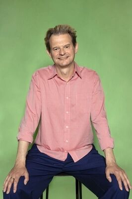 Portretfoto ensemblelid Gillis Biesheuvel van Het Zuidelijk Toneel, die poseert tegen een groene achtergrond.