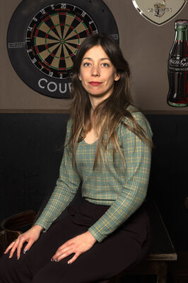 Regisseur Jessie L'Herminez poseert in bruin café