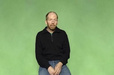 Portretfoto maker Jetse Batelaan van Het Zuidelijk Toneel, poserend met een gekke bek tegen een groene achtergrond.