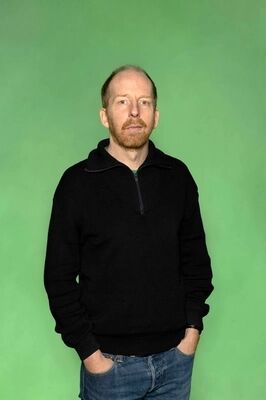 Portretfoto maker Jetse Batelaan van Het Zuidelijk Toneel, poserend tegen een groene achtergrond.