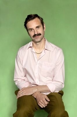 Portretfoto ensemblelid Joep van der Geest van Het Zuidelijk Toneel, die poseert tegen een groene achtergrond.