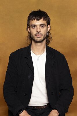 Portretfoto maker Koen van Seuren van Het Zuidelijk Toneel, poserend tegen een okergele achtergrond.