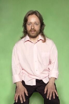Portretfoto ensemblelid Louis van der Waall van Het Zuidelijk Toneel, die poseert tegen een groene achtergrond.