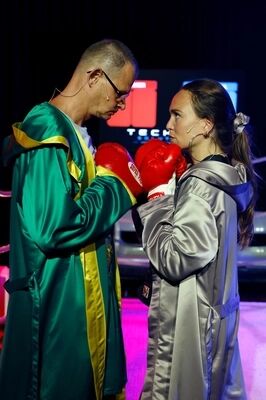 Twee boksers staan tegenover elkaar in de ring, gekleed in bokskleding en met handschoenen aan, klaar om te vechten.