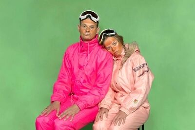 Twee personen met fel roze ski pakken en ski brillen voor een groen doek.