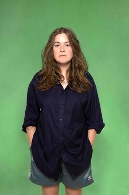 Portretfoto maker Silke van Kamp van Het Zuidelijk Toneel, poserend tegen een groene achtergrond.
